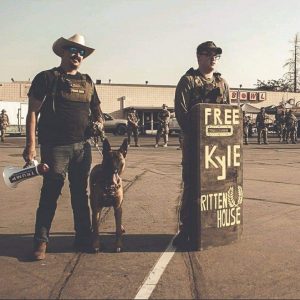 Christopher Young (left) next to a homemade shield that says "Free Kyle Rittenhouse" next to the Proud Boys logo in Atwater, CA